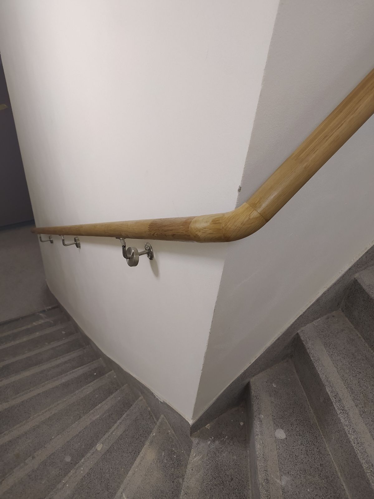 Detail ohybu dřevěného madla s nerezovými držáky